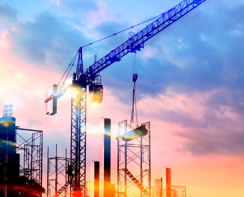 tower cranes at construction site with sun