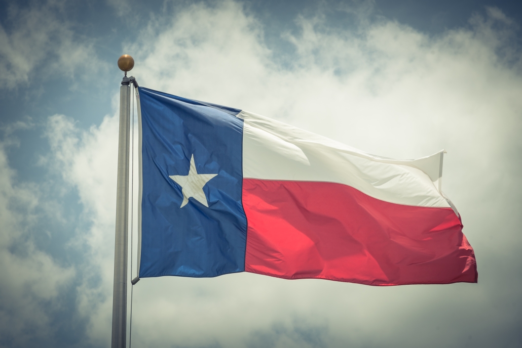 Large Texas (The Lone Star) flag waving on flag pole with cloud blue sky. Windy and sunny day with waving flag blowing/flowing. Ruffled Texas flag. Room for text, copy space. Vintage tone.