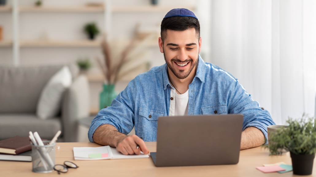 Smiling israeli man working on laptop at home