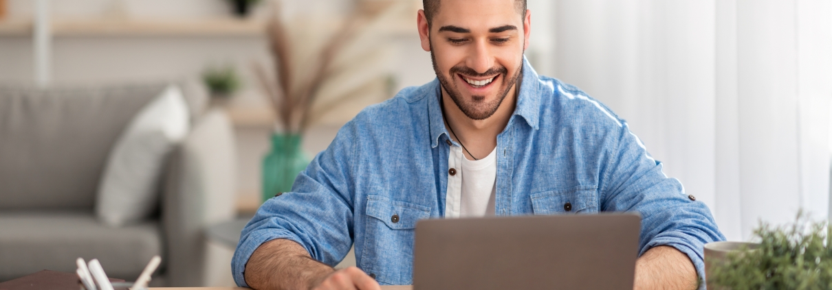 Smiling israeli man working on laptop at home