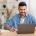 Smiling israeli man working on laptop at home