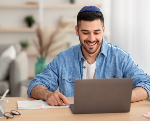 Smiling israeli man working on laptop at home