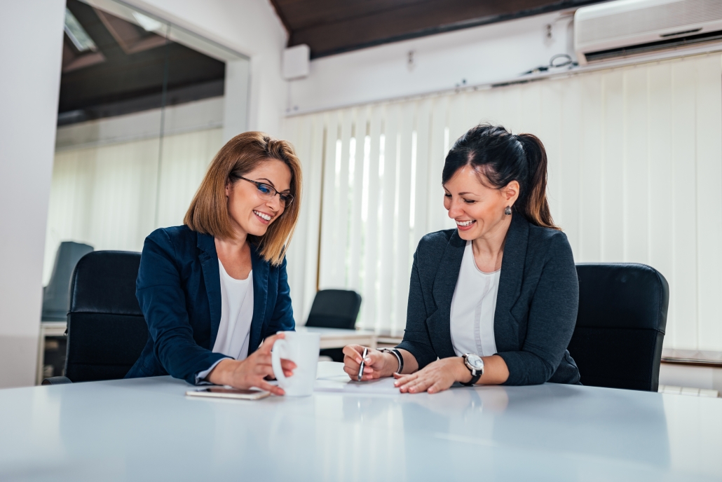 Two cheerful business woman working at conference table.