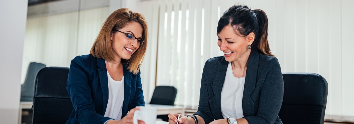 Two cheerful business woman working at conference table.