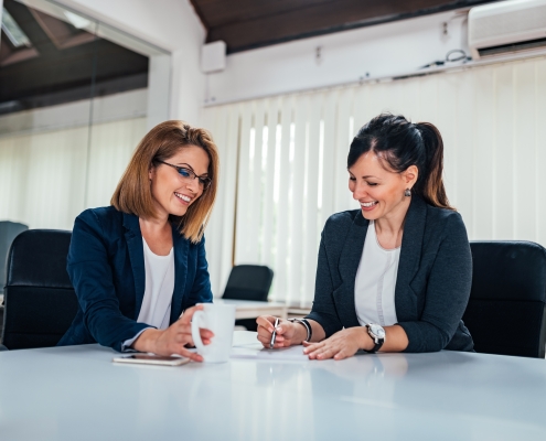 Two cheerful business woman working at conference table.