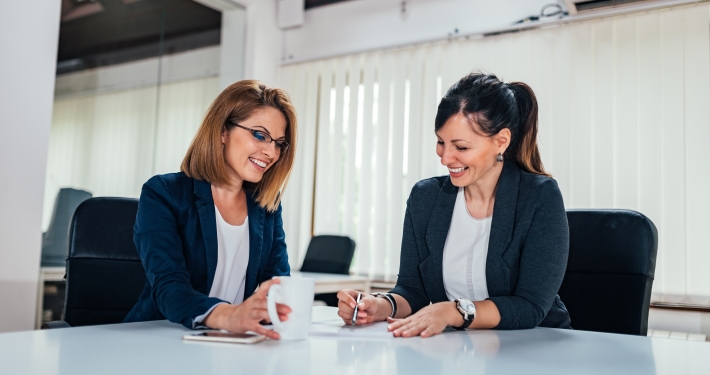 Two cheerful business woman working at conference table.