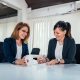 Two cheerful business woman working at conference table.